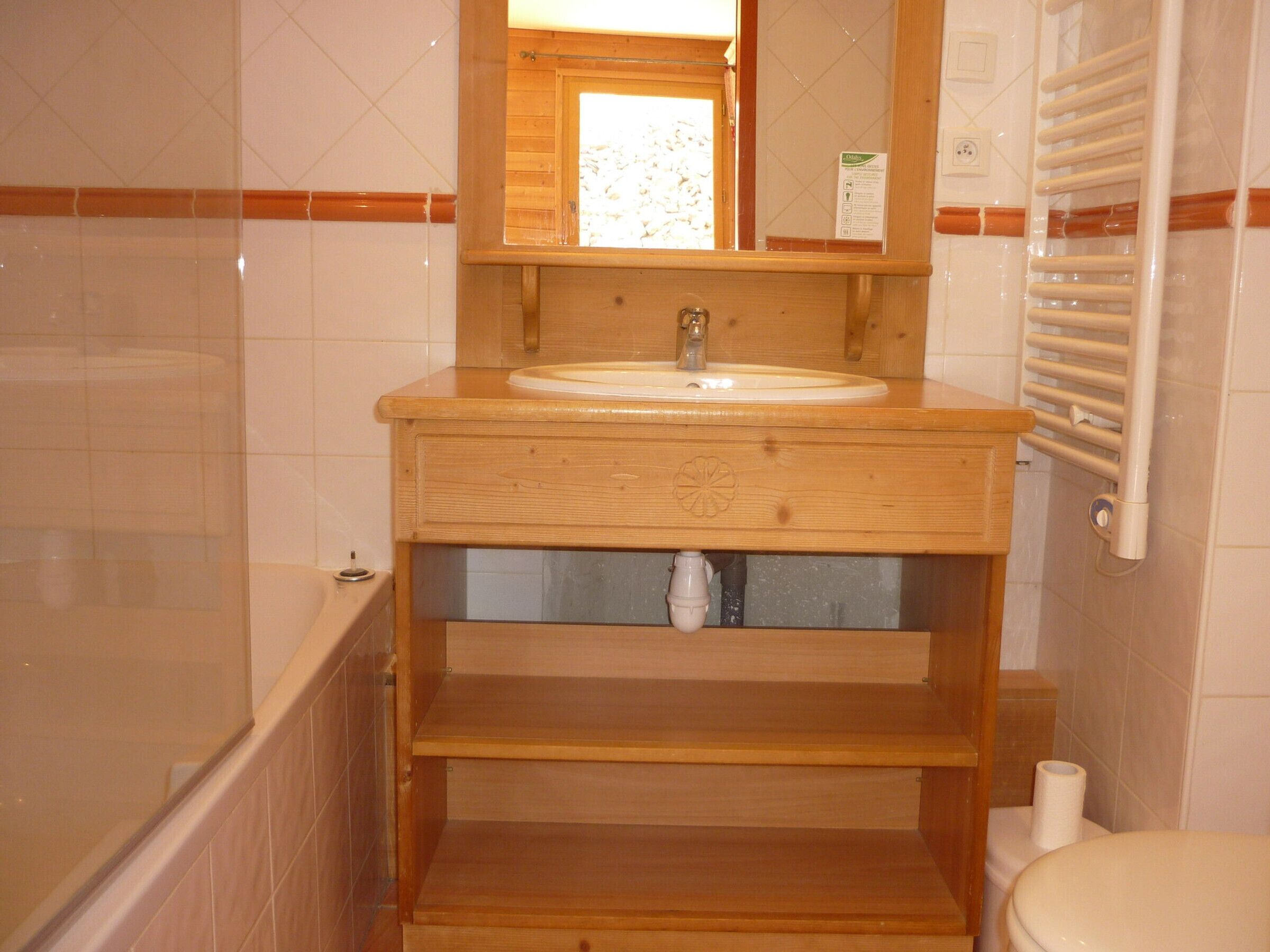 A bathroom with a wooden vanity, a sink, a mirror, a towel rack, and a toilet.