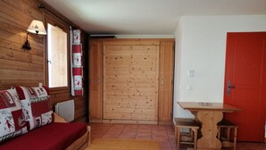 Una stanza accogliente con un divano di legno, un tavolino e una porta rossa.