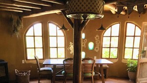 A cozy room with a wooden table, two chairs, a sofa, and a large window with a view of greenery. - Ecological mud house (Maldonado)