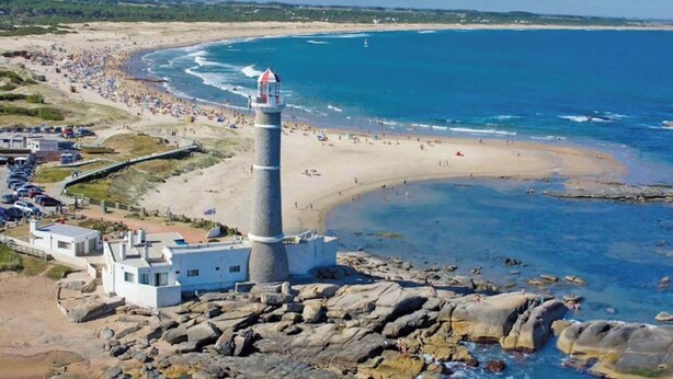 A coastal scene with a lighthouse, beach, and rocky shoreline. - Ecological mud house (Maldonado)