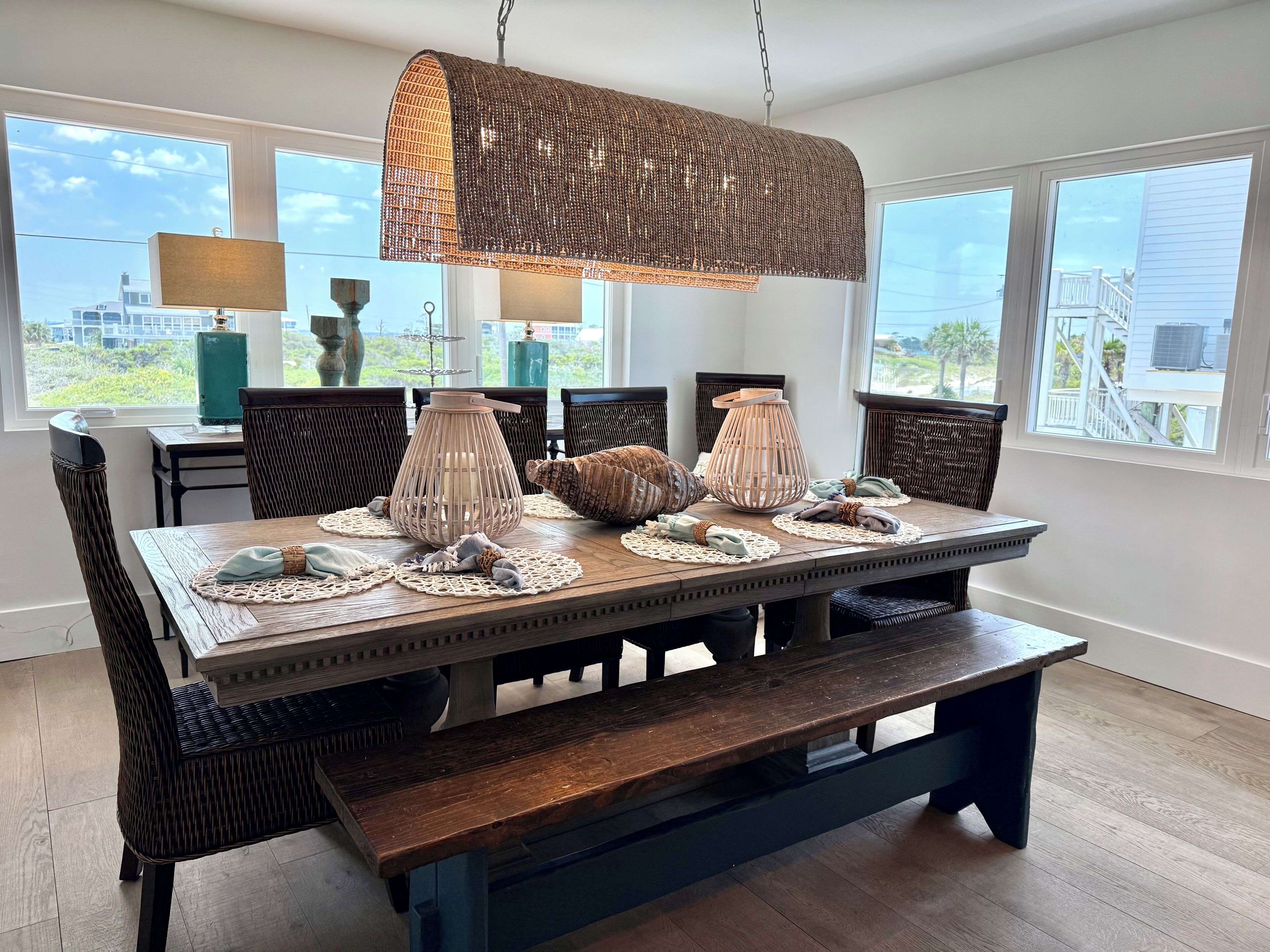 A dining area with a wooden table, woven chairs, and a hanging light fixture.
