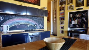 Eine Küche mit einer Kreidetafel, einer Kaffeemaschine und einem Bücherregal voller Bücher.