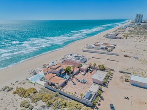 Luchtbeeld van een landgoed aan de kust met een zwembad, een tennisbaan en een strand.