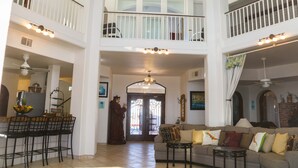 Un espacio habitable amplio, distribuido en varios niveles, con comedor, un conjunto de sofás y una escalera que conduce a un balcón superior.
