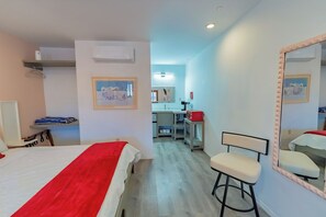 Ein Hotelzimmer mit Bett, Stuhl, Schreibtisch, Spiegel und einer Küchenzeile.