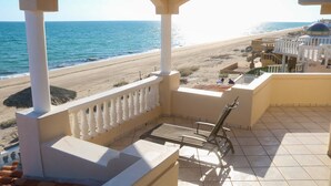 Un balcón con vista a la playa, un área de piscina y un edificio con cúpula.