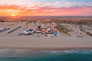Een strandhuis met een groot woonhuis, zwembad en parkeerplaats.