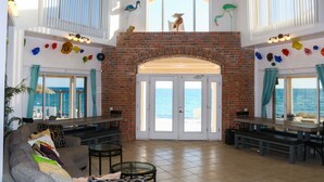 Amplia sala de estar con chimenea de ladrillo, grandes ventanales con vista al mar y un balcón con vistas al océano.
