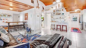 Un ampio soggiorno con soffitto in legno, una zona pranzo e una cucina.