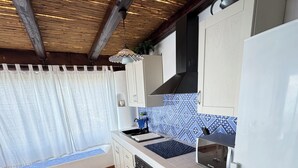 A compact kitchen with white cabinets, a black stove, and a white refrigerator. - The casuzza of RE !! (Malfa)