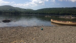 Un lago tranquilo con orilla rocosa, un canoa y un bote pequeño.