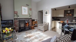 Una sala de estar con chimenea, televisor y comedor con mesa de vidrio.