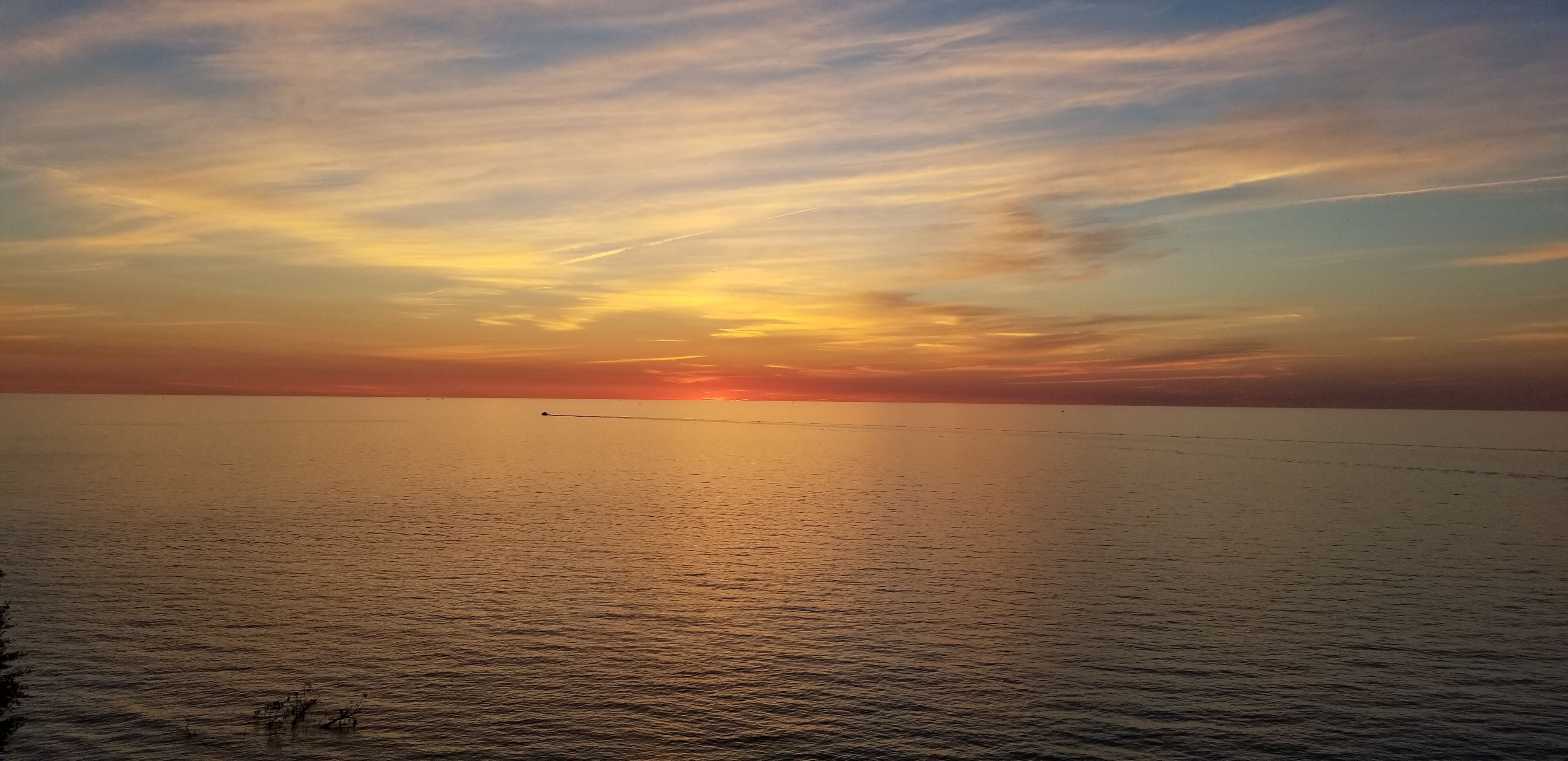 Un coucher de soleil sur une mer calme, avec un horizon lointain.