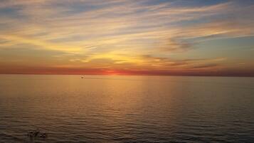 Un coucher de soleil sur une mer calme, avec un horizon lointain.