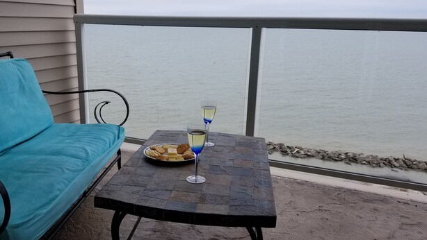 Ein Balkon mit einem blauen Sofa und einem Tisch mit einem Weinglas und Snacks.