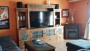 Ein Wohnzimmer mit einem großen Flachbildfernseher, Holzausstattung, einem Kamin und einem Poster an der Wand.
