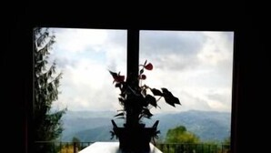 Una mesa con un florero en el centro, con vistas a montañas y un cielo nublado.