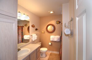 Une salle de bain avec un lavabo, des toilettes et un miroir. Des serviettes sont accrochées au mur et il y a un rideau de douche.