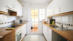 A compact kitchen with white cabinets, a microwave, a sink, and a window. - 1081 Apartment Poseidon (Nerja)