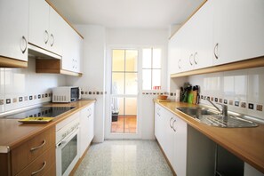 A compact kitchen with white cabinets, a microwave, a sink, and a window.