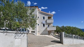 Un immeuble à plusieurs étages, doté d’une façade en pierre, d’une entrée sécurisée par un portail et d’une allée pavée menant à l’entrée.
