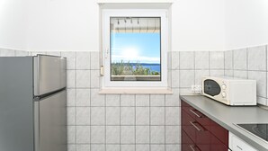 Une cuisine équipée d’une fenêtre intégrée, d’un réfrigérateur, d’un four à micro-ondes et de placards.
