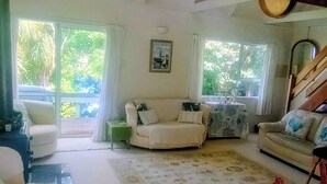 Una sala de estar con un sofá, un sillón, una mesa y una escalera.