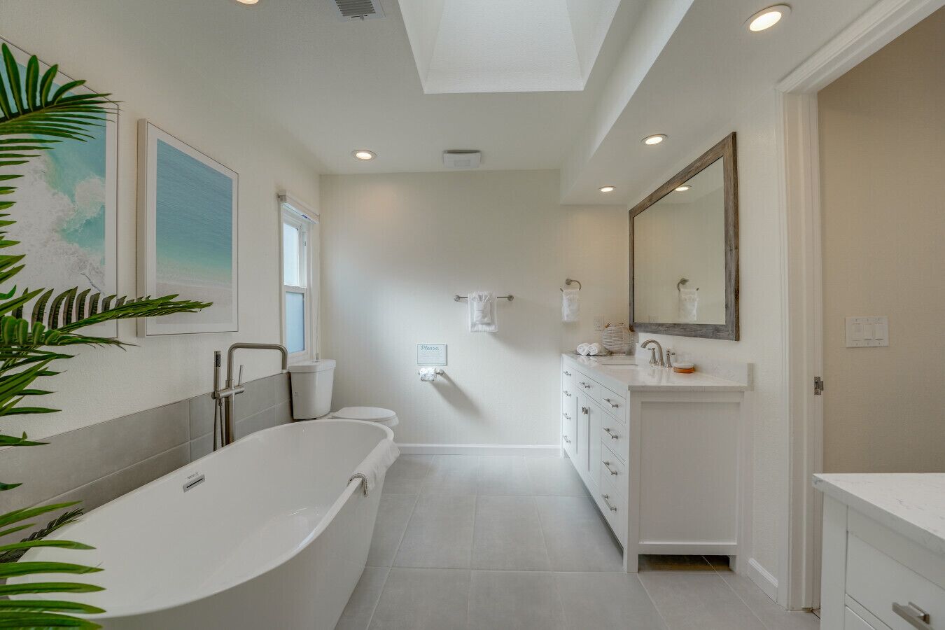 A modern bathroom with a freestanding bathtub, a vanity with a mirror, and a toilet.