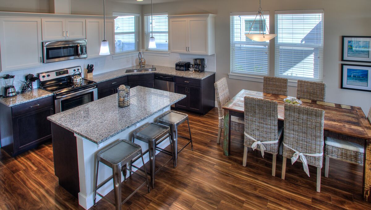A modern kitchen with granite countertops, stainless steel appliances, and a central island with bar stools.