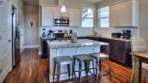 A modern kitchen with white cabinets, a stainless steel oven, and a granite countertop. - Sea Turtle Cottage - Oyhut Bay Seaside Village (Ocean Shores)