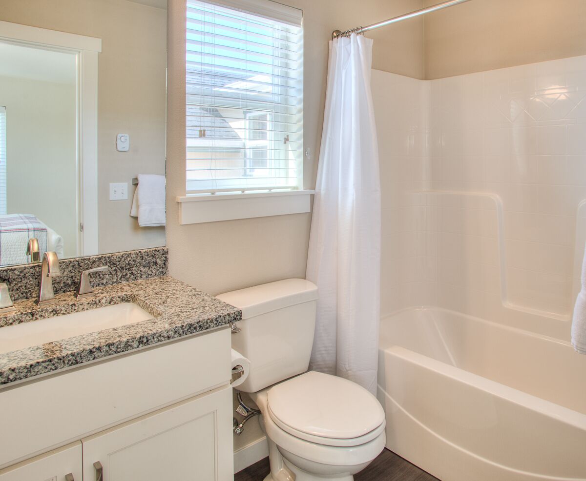 Un baño con lavamanos de granito, inodoro y bañera.