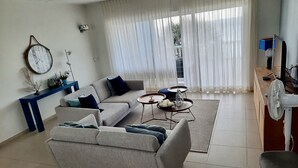 Una sala de estar con sofá, una mesa de centro y una zona de comedor con un ventilador.