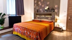 A bedroom with a bed, a radiator, a window with curtains, a wall-mounted shelf with decorative items, and a bedside table with a lamp. - Self catering Residence Masnaiot for 2 people (Cossano Belbo)