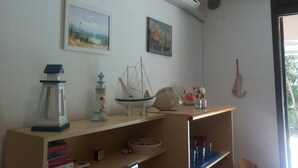Ein Zimmer mit einer Holzhilfe, die verschiedene Gegenstände zeigt, einer Klimaanlage an der Wand und zwei Gemälden.