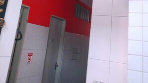 A hallway with white walls, a red accent wall, and a door marked with a "No Smoking" sign. - Pousada Refúgio (João Pessoa)