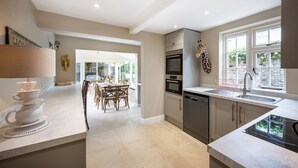 A modern kitchen with a dining area, featuring a large window, built-in oven, and a sink. - The Old Manor House, Brancaster, Norfolk (King's Lynn)