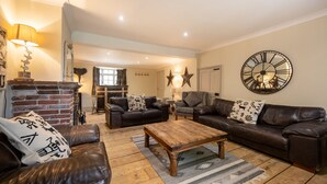 A cozy living room with leather sofas, a wooden coffee table, and a large wall clock. - The Old Manor House, Brancaster, Norfolk (King's Lynn)