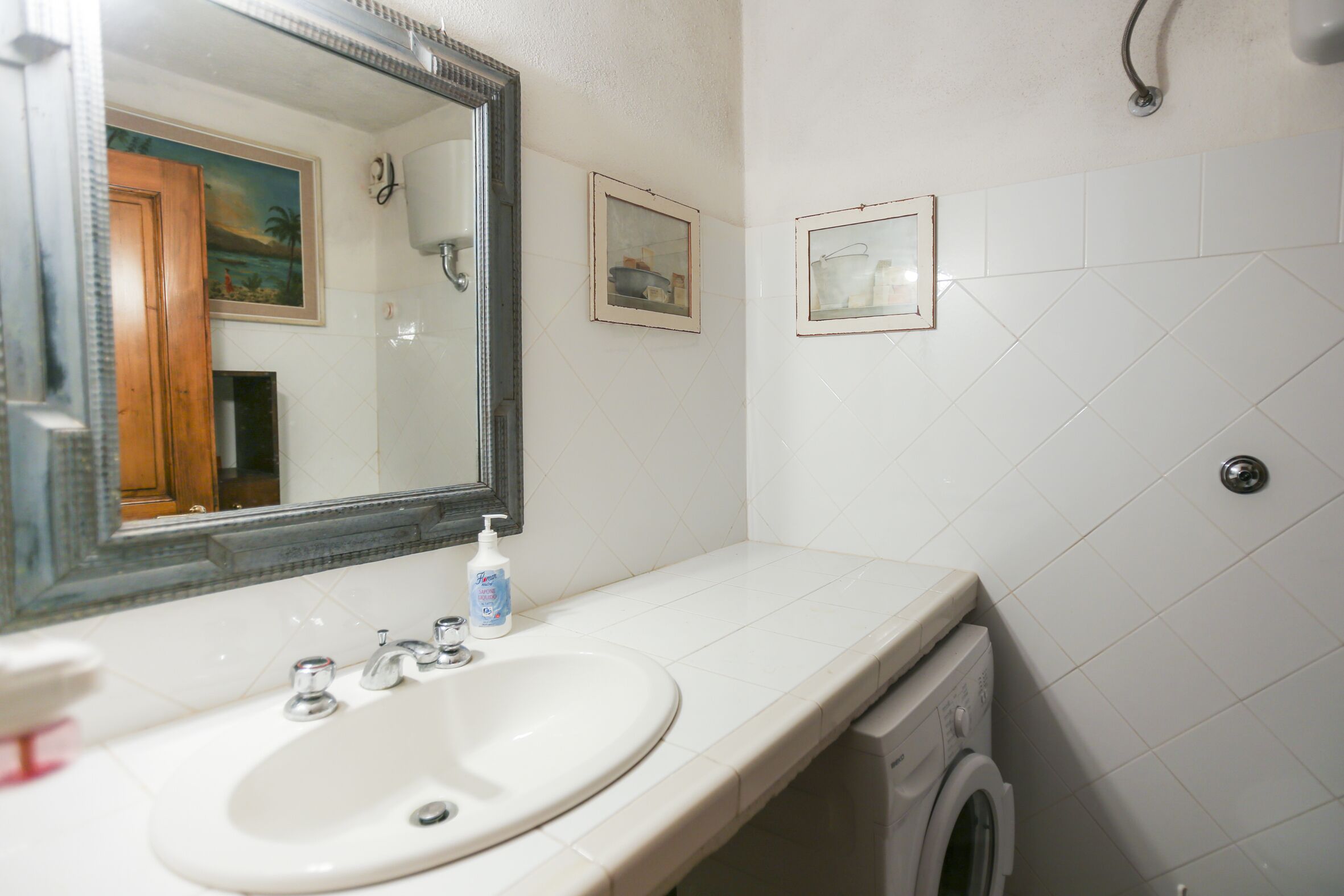 Un baño con lavabo, espejo y lavadora.