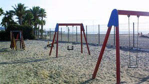 Une aire de jeux sur la plage avec des balançoires et un toboggan.