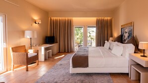 Una habitación de hotel con una cama, un escritorio, una silla, un televisor y un cuadro en la pared.
