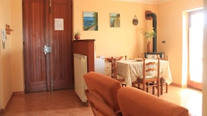 A dining area with a table and chairs, a radiator, a wooden door, and a wall with pictures. - Attic with flowers. (Abatemarco)