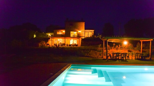 Ein Pool mit einer eingelassenen Sitzgruppe und einem überdachten Essbereich im Freien.