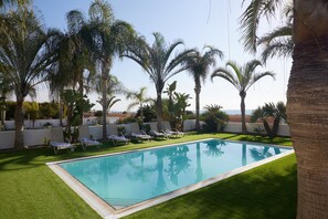 Une piscine entourée de palmiers et de chaises longues.