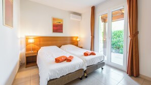 A hotel room with two beds, a wooden headboard, a nightstand with a lamp, and a window with curtains. - Villa Lune for 10 people with private pool (Vallon Pont D'Arc)