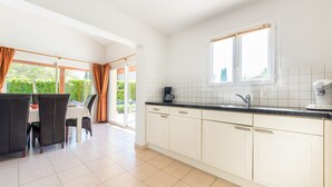 A modern kitchen with white cabinets, a black countertop, and a window above the sink. - Villa Lune for 10 people with private pool (Vallon Pont D'Arc)