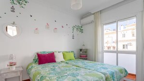 Un dormitorio con cama, mesita de noche, ventana y pegatinas decorativas en la pared.