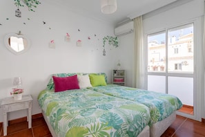 Een slaapkamer met een bed, nachtkastje, raam en decoratieve muurstickers.