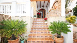 Una escalera con baldosas de terracota y diseños decorativos, que lleva a una puerta adornada con un adorno rojo.