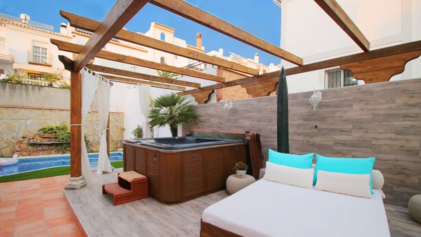 Un dormitorio con cama de madera, un jacuzzi y vista a una piscina.