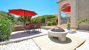 An outdoor patio with red umbrellas, a fire pit, and a seating area with chairs and tables. - LUKAS 1, charming 2-bedroom apartment (Okrug Gornji)
